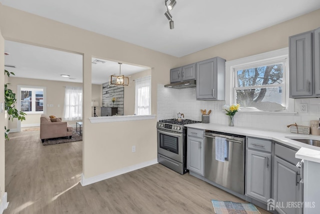 kitchen with light wood-style floors, tasteful backsplash, appliances with stainless steel finishes, and gray cabinetry