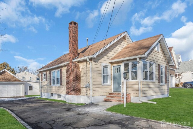 bungalow with a garage, an outbuilding, and a front lawn