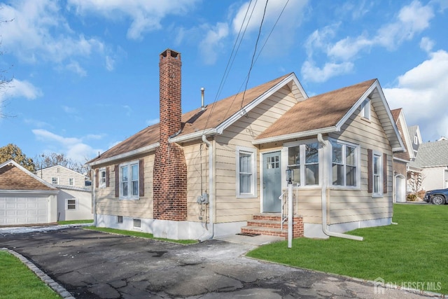 view of front of home featuring a chimney, entry steps, a front lawn, an outdoor structure, and a detached garage