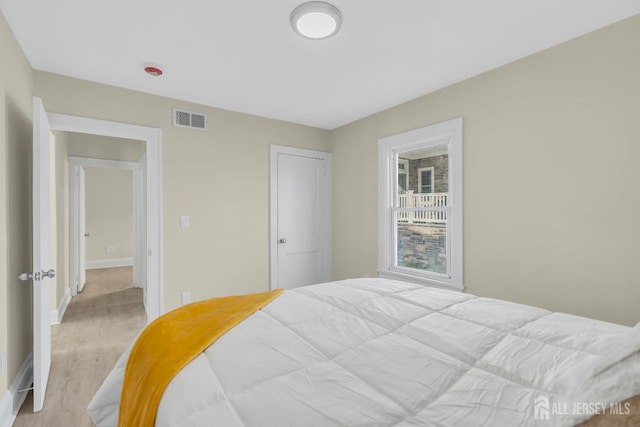 bedroom featuring visible vents, light wood-type flooring, and baseboards