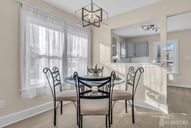 dining area with an inviting chandelier, light wood-type flooring, and baseboards