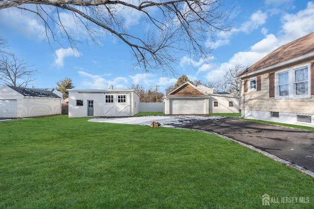 view of yard with a detached garage, an outdoor structure, and fence