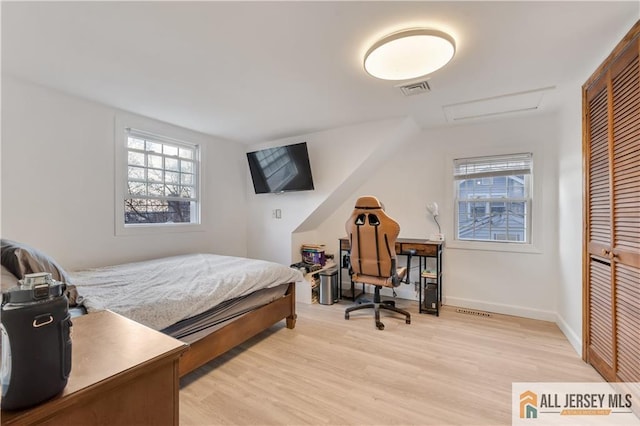 bedroom featuring multiple windows, a closet, and light hardwood / wood-style flooring