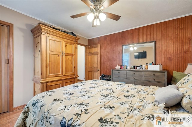 bedroom featuring crown molding, wooden walls, ceiling fan, and light hardwood / wood-style floors