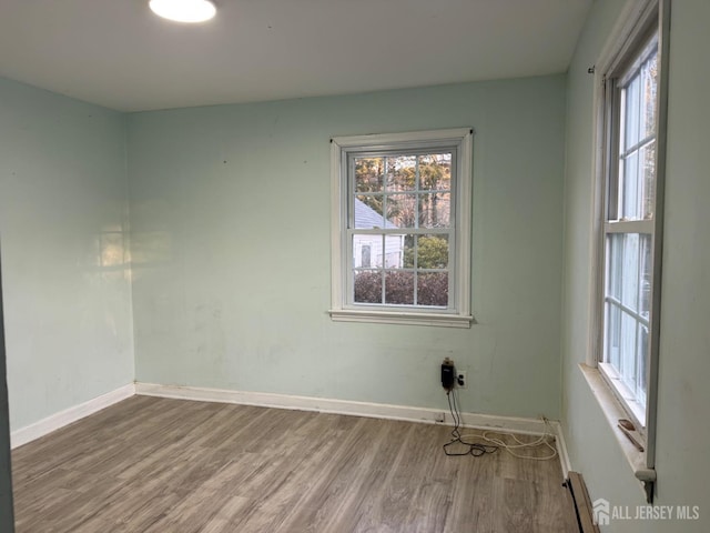 unfurnished room with a baseboard radiator, plenty of natural light, and light wood-type flooring