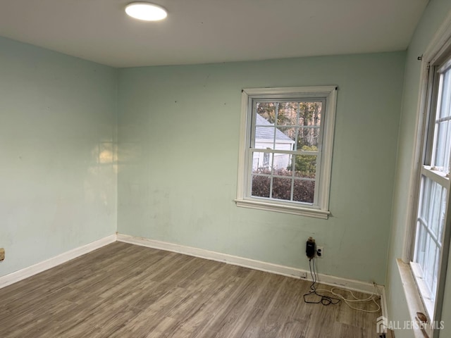 empty room with wood finished floors, a wealth of natural light, and baseboards