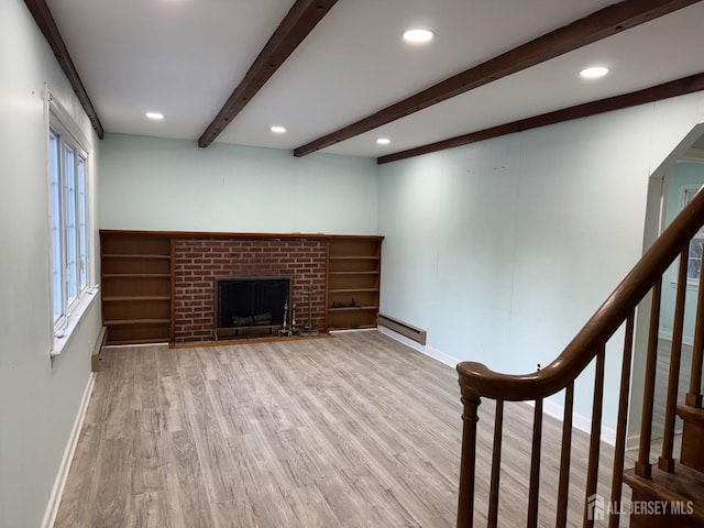 interior space featuring a fireplace, a baseboard radiator, beamed ceiling, and light wood-type flooring