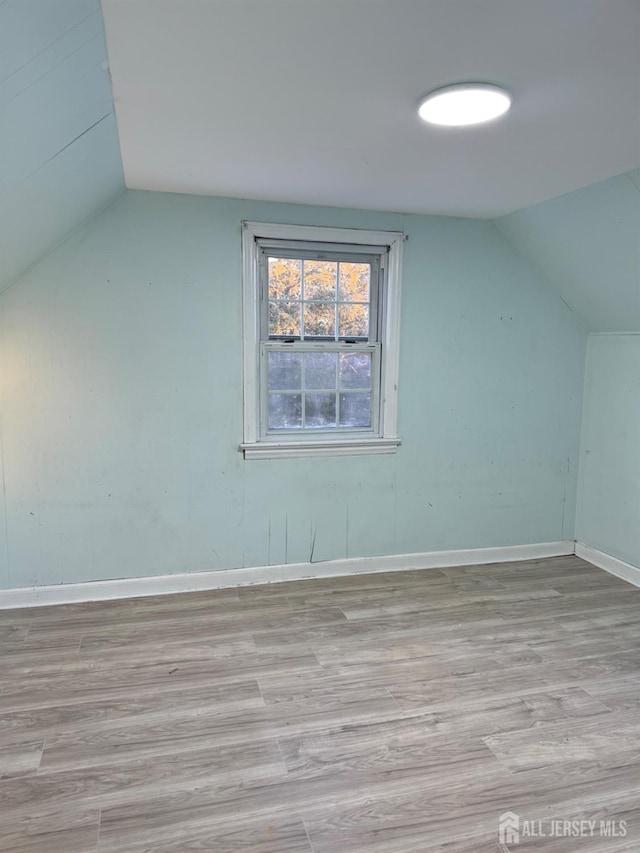 bonus room with vaulted ceiling and light hardwood / wood-style flooring