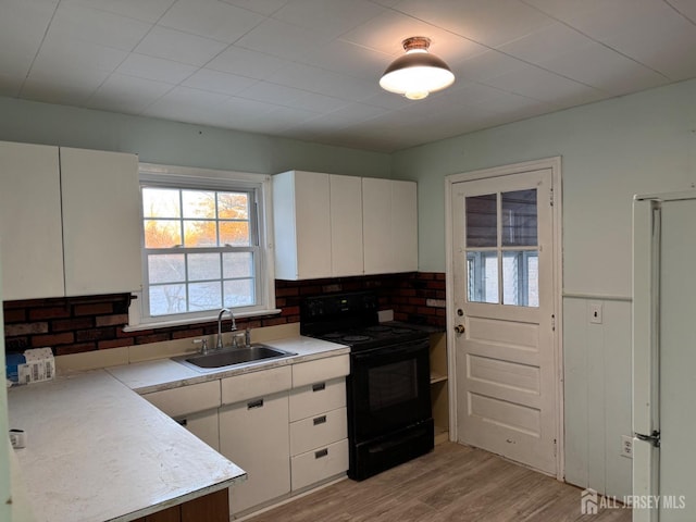 kitchen featuring white cabinetry, sink, black range with electric cooktop, and white refrigerator