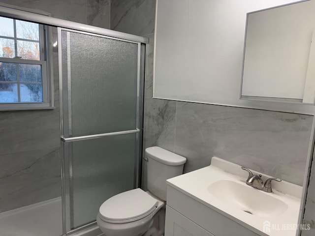 bathroom featuring vanity, toilet, an enclosed shower, and tile walls