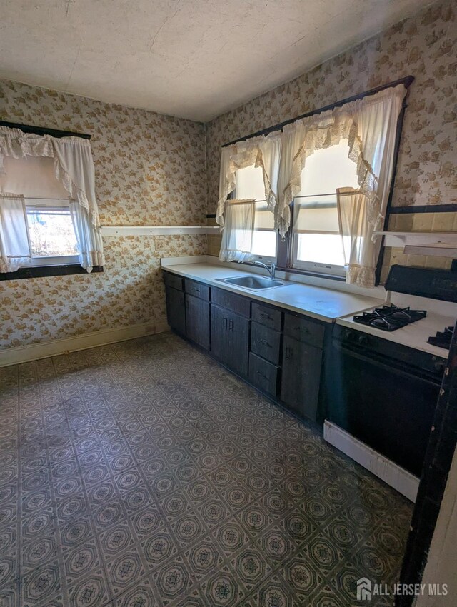 kitchen featuring plenty of natural light, gas range oven, sink, and a textured ceiling