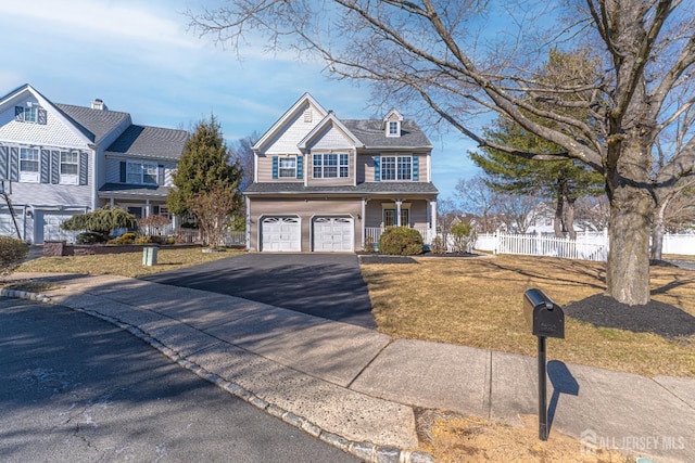 view of front of house with aphalt driveway, a garage, a front yard, and fence