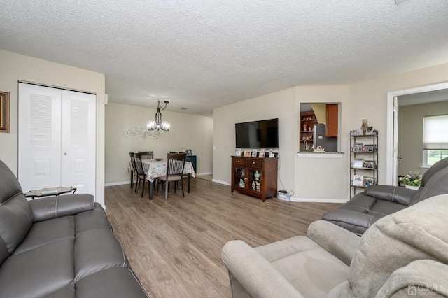 3002 Lighthouse Ln, Sayreville, NJ 08859 - living room featuring a chandelier, wood finished floors, a textured ceiling, and baseboards
