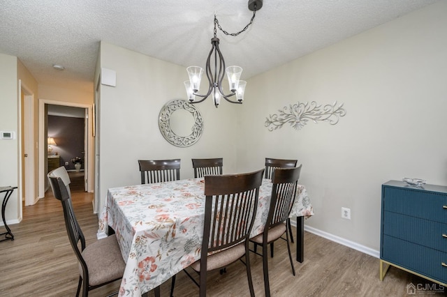 3002 Lighthouse Ln, Sayreville, NJ 08859 - dining room with wood finished floors, a chandelier, baseboards, and a textured ceiling