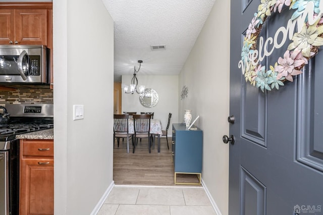 3002 Lighthouse Ln, Sayreville, NJ 08859 - entryway featuring baseboards, light tile patterned floors, a textured ceiling, and a chandelier