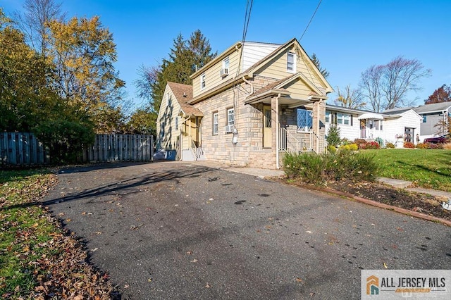 view of front facade featuring fence, stone siding, and driveway