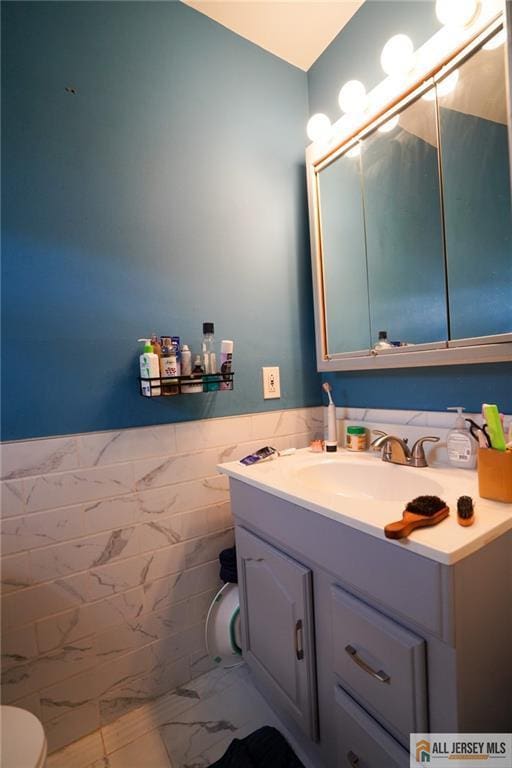 3060 Bordentown Ave, Old Bridge, NJ 08859 - half bathroom with marble look tiles, toilet, vanity, wainscoting, and tile walls