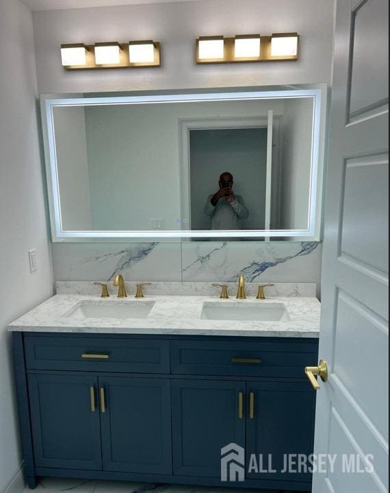 bathroom with double vanity, backsplash, and a sink