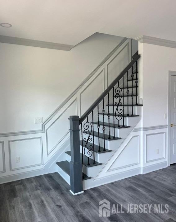 stairway featuring a decorative wall and wood finished floors