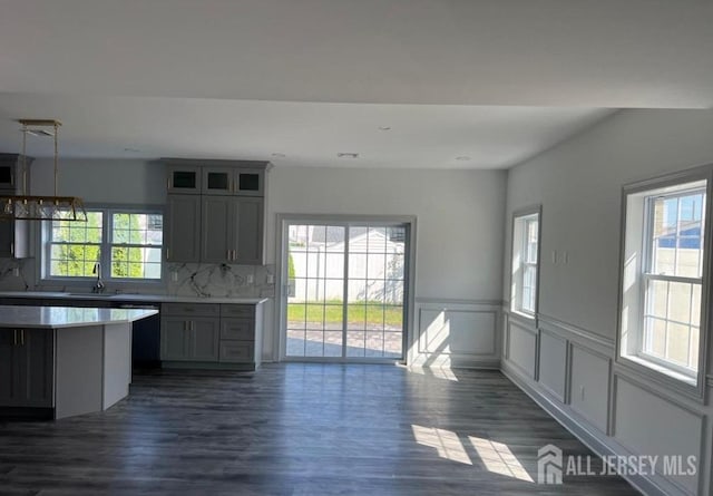 kitchen featuring dark wood-type flooring, backsplash, a healthy amount of sunlight, and light countertops