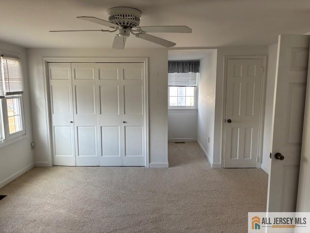 unfurnished bedroom with ceiling fan, light colored carpet, and a closet