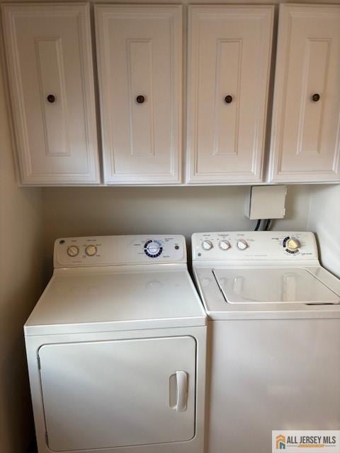 laundry area featuring separate washer and dryer and cabinets