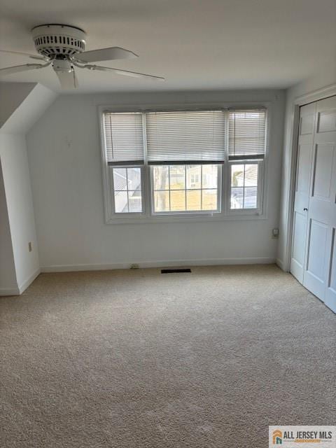 additional living space with visible vents, baseboards, a ceiling fan, light colored carpet, and lofted ceiling