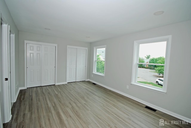 54 Castle Pointe Blvd, Piscataway, NJ 08854 - unfurnished bedroom featuring multiple closets, baseboards, and wood finished floors