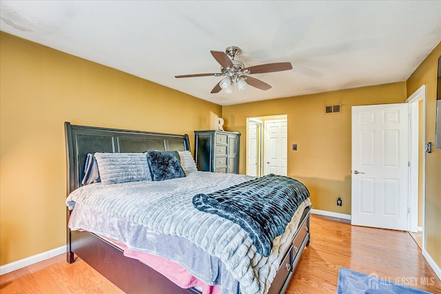 bedroom featuring visible vents, ceiling fan, light wood-style flooring, and baseboards