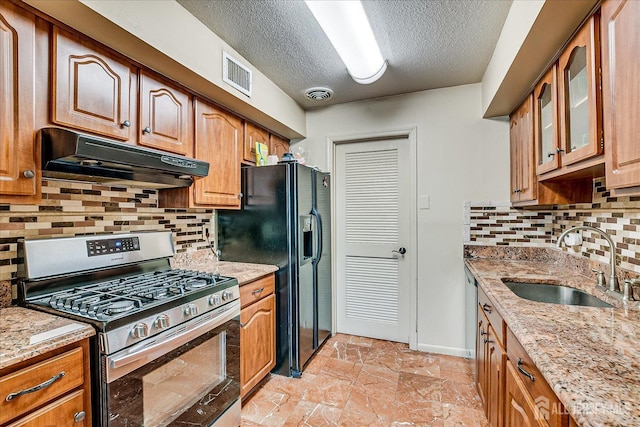 kitchen featuring stainless steel gas range, under cabinet range hood, visible vents, and a sink