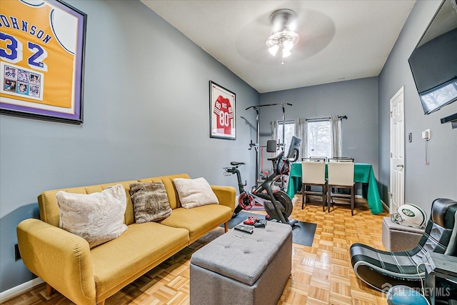 living area with ceiling fan and baseboards