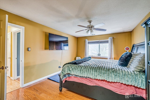 bedroom with a textured ceiling, parquet floors, a ceiling fan, and baseboards