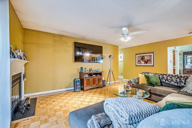 living room with ceiling fan, a glass covered fireplace, visible vents, and baseboards