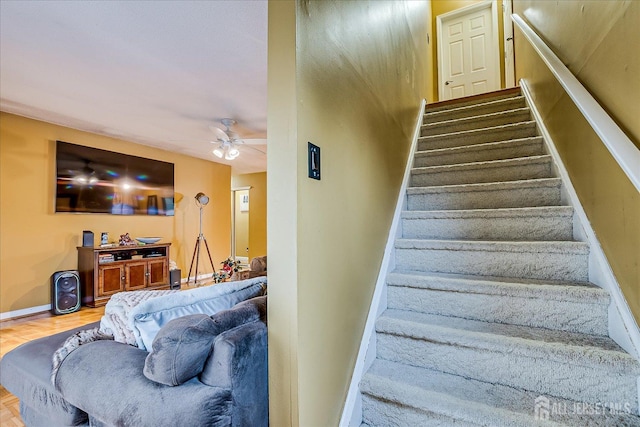 stairway featuring ceiling fan, baseboards, and wood finished floors