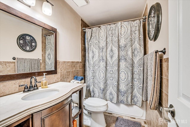 bathroom with a wainscoted wall, tile walls, toilet, shower / tub combo, and vanity