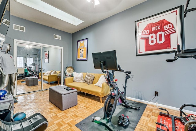 workout room featuring a skylight, visible vents, and baseboards