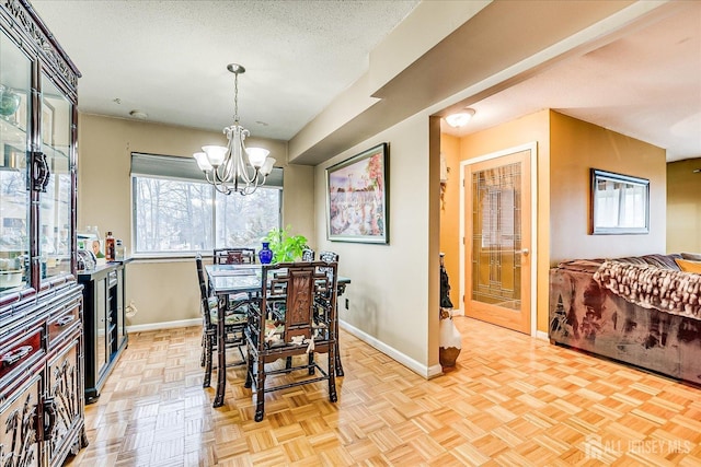 dining room featuring an inviting chandelier, baseboards, and a textured ceiling