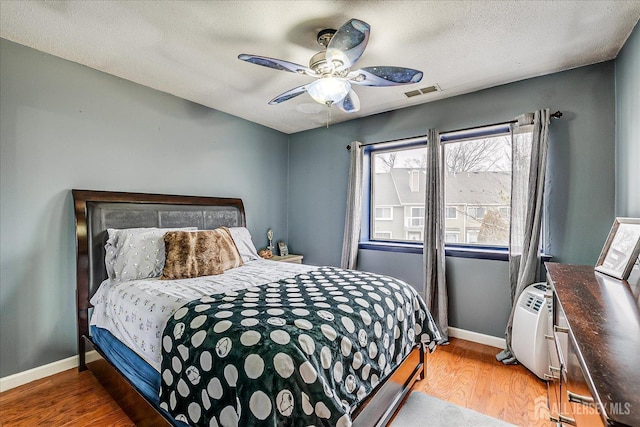 bedroom with light wood finished floors, visible vents, baseboards, and ceiling fan