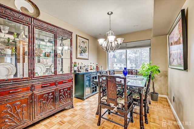 dining area featuring a textured ceiling, a bar, baseboards, and an inviting chandelier