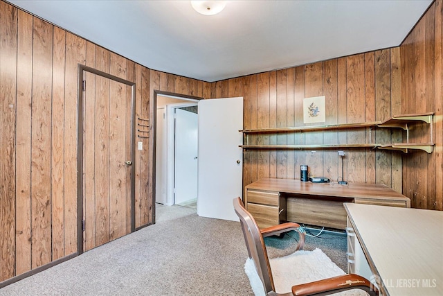 office space with carpet, wooden walls, and built in desk