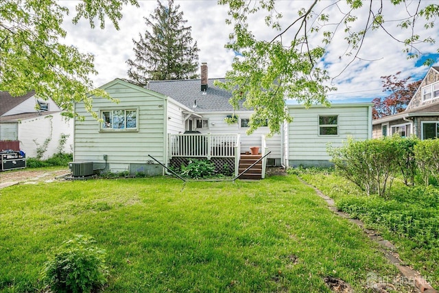 back of property with a wooden deck, a lawn, a chimney, and central AC unit