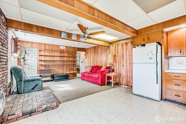 living room with wood walls, a ceiling fan, and light carpet