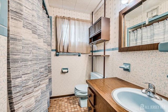 full bath with toilet, tile walls, a shower with shower curtain, vanity, and wallpapered walls
