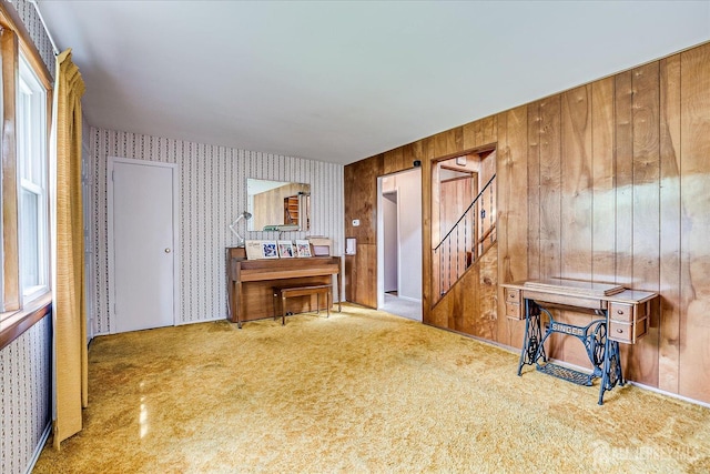 living area featuring wallpapered walls, stairway, carpet, and wooden walls