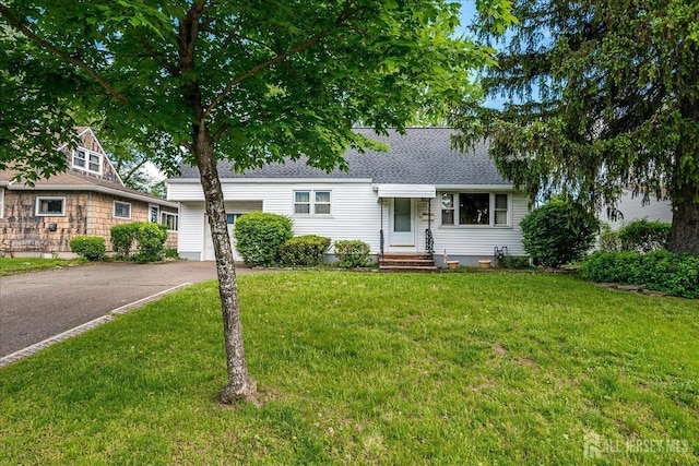 view of front of home with driveway, a front lawn, and a shingled roof