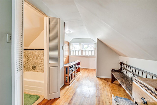 additional living space with light wood-style flooring, vaulted ceiling, and baseboards
