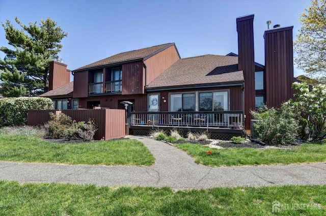 rear view of property featuring roof with shingles, fence, and a chimney