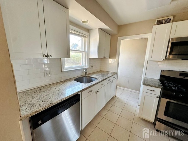 130 Maple Pl S, Plainfield, NJ 07080 - kitchen featuring appliances with stainless steel finishes, a sink, light stone counters, white cabinetry, and light tile patterned flooring