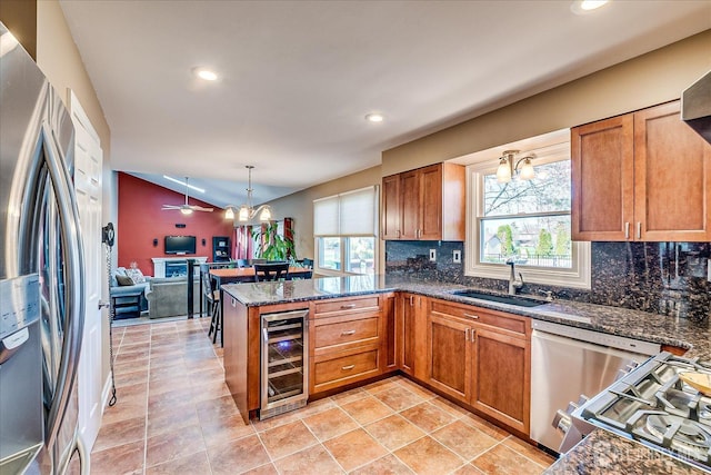 kitchen with beverage cooler, stainless steel appliances, a sink, a peninsula, and open floor plan