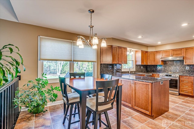 kitchen featuring a notable chandelier, a sink, decorative backsplash, electric range, and under cabinet range hood